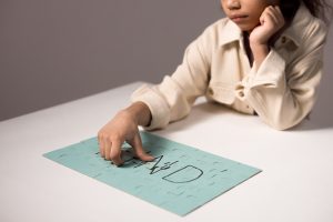 A young child solving a blue puzzle, engaging in thoughtful play at a table.
